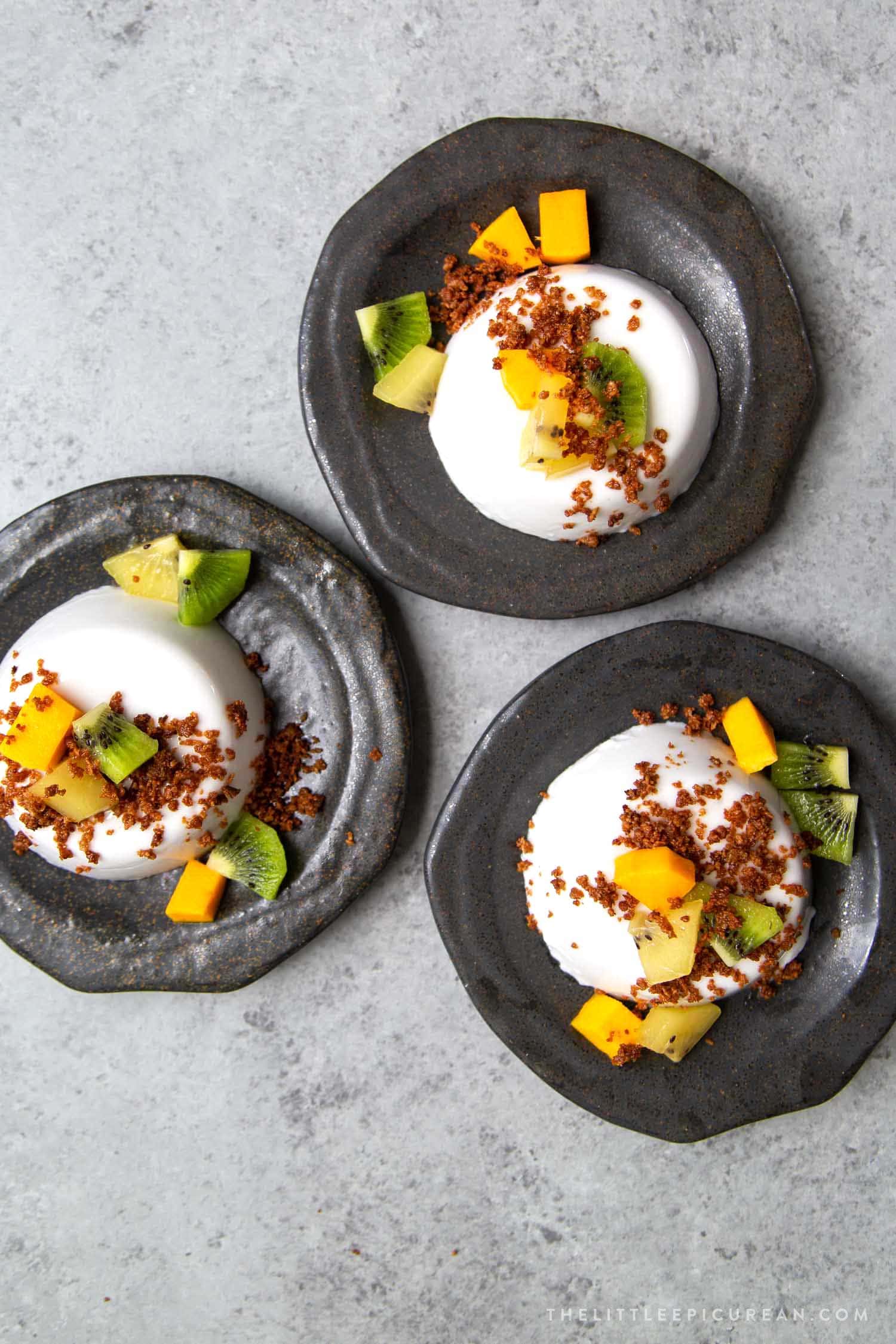 Coconut Panna Cotta served with latik and fresh fruits. Latik is from the Philippines. It is fried coconut milk curds.