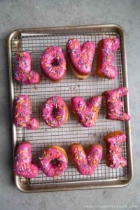 Letter Donuts with pink glaze and rainbow sprinkles. Send your loved ones using donuts!