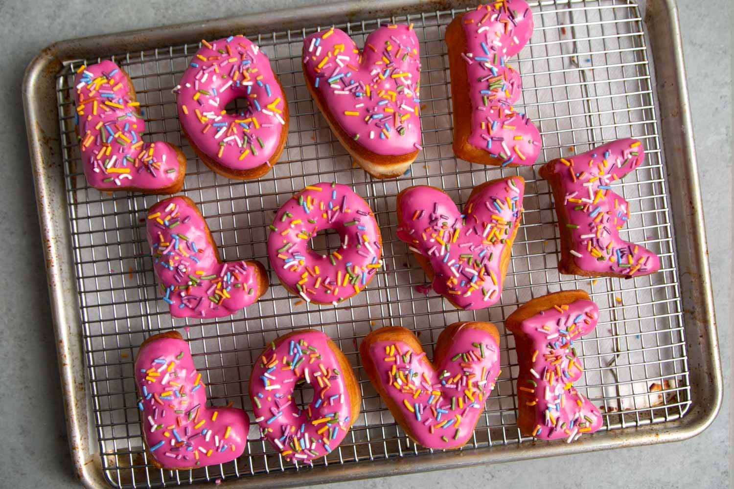 Letter Donuts with pink glaze and rainbow sprinkles. Send your loved ones using donuts!