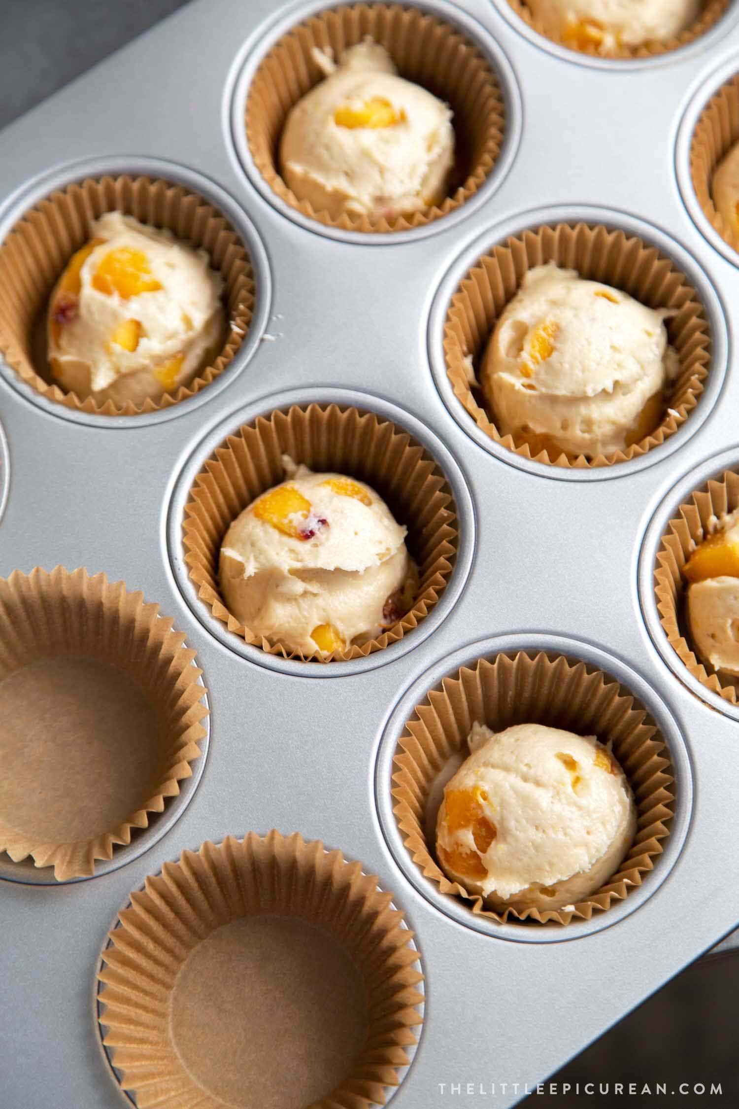 Almond Streusel Peach Muffins. Batter is divided into prepared muffin tin using an ice cream scooper.