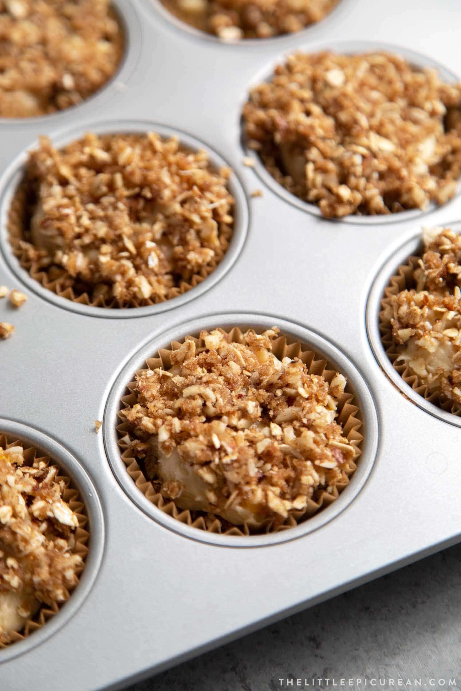 Almond Streusel Peach Muffins. Batter is divided into prepared muffin tin using an ice cream scooper and topped with almond oat streusel.