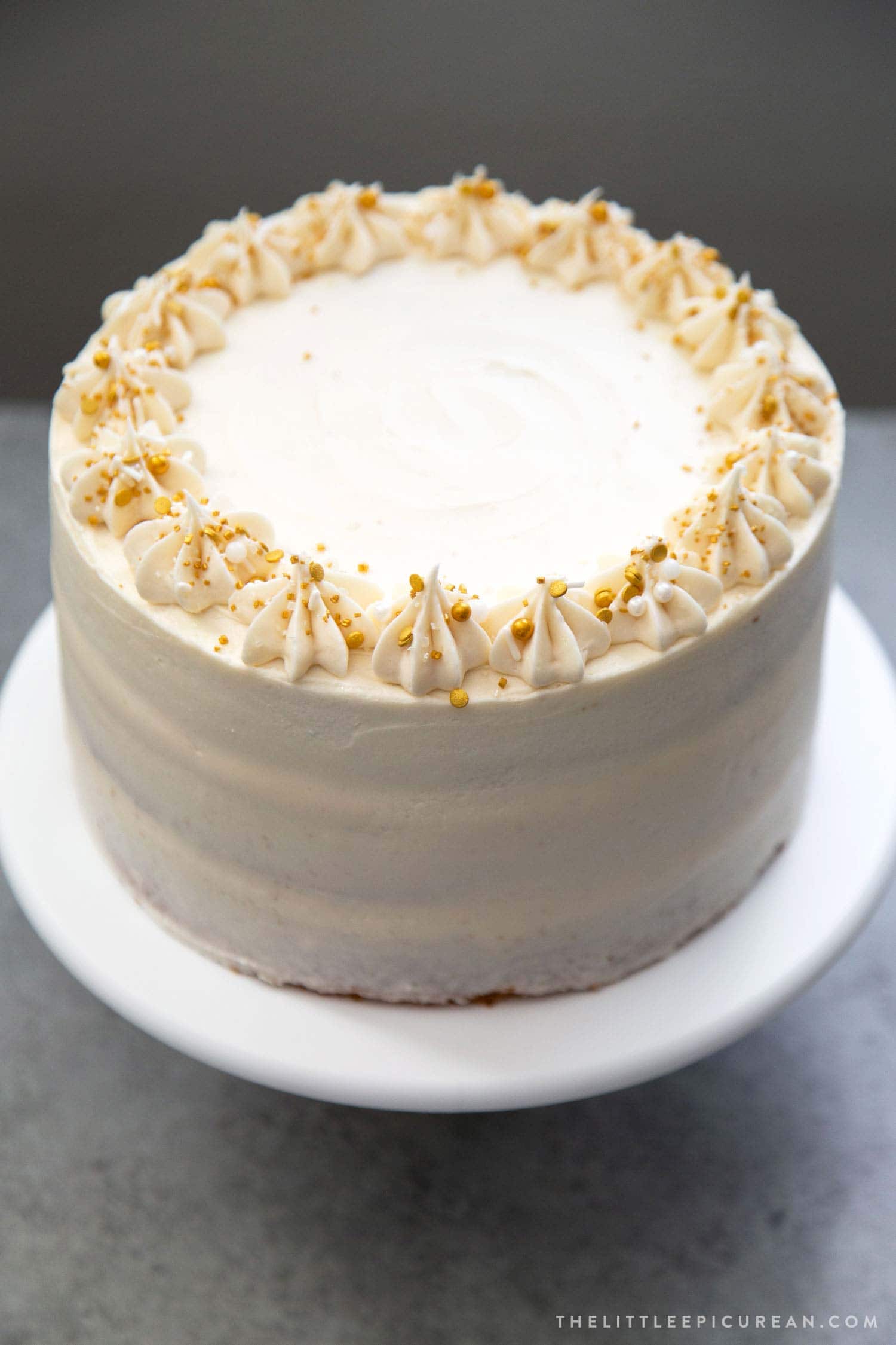 Apple Cider Layer Cake decorated with gold sprinkles on white cake stand.