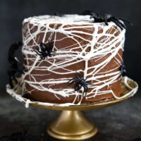 Chocolate Spider Web Cake. Three layer chocolate cake frosted with simple chocolate buttercream and decorated with marshmallow spider webs. It's the perfect Halloween treat!