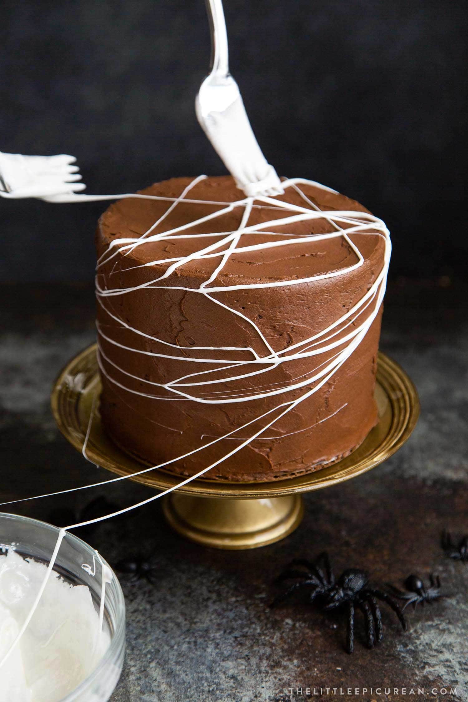 Chocolate Spider Web Cake. Three layer chocolate cake frosted with simple chocolate buttercream and decorated with marshmallow spider webs. It's the perfect Halloween treat!