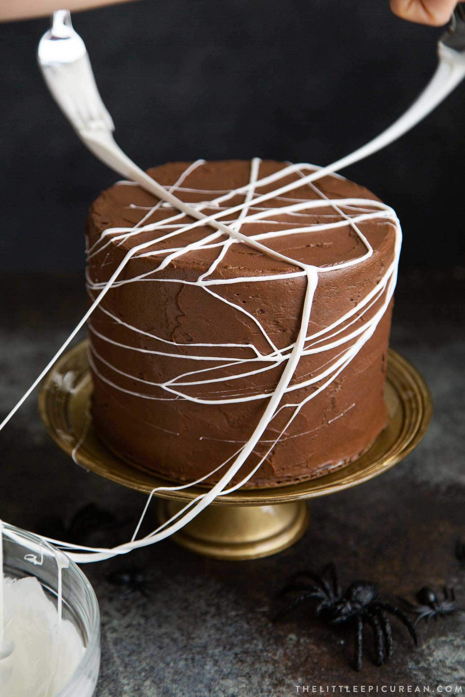 Chocolate Spider Web Cake. Three layer chocolate cake frosted with simple chocolate buttercream and decorated with marshmallow spider webs. It's the perfect Halloween treat!