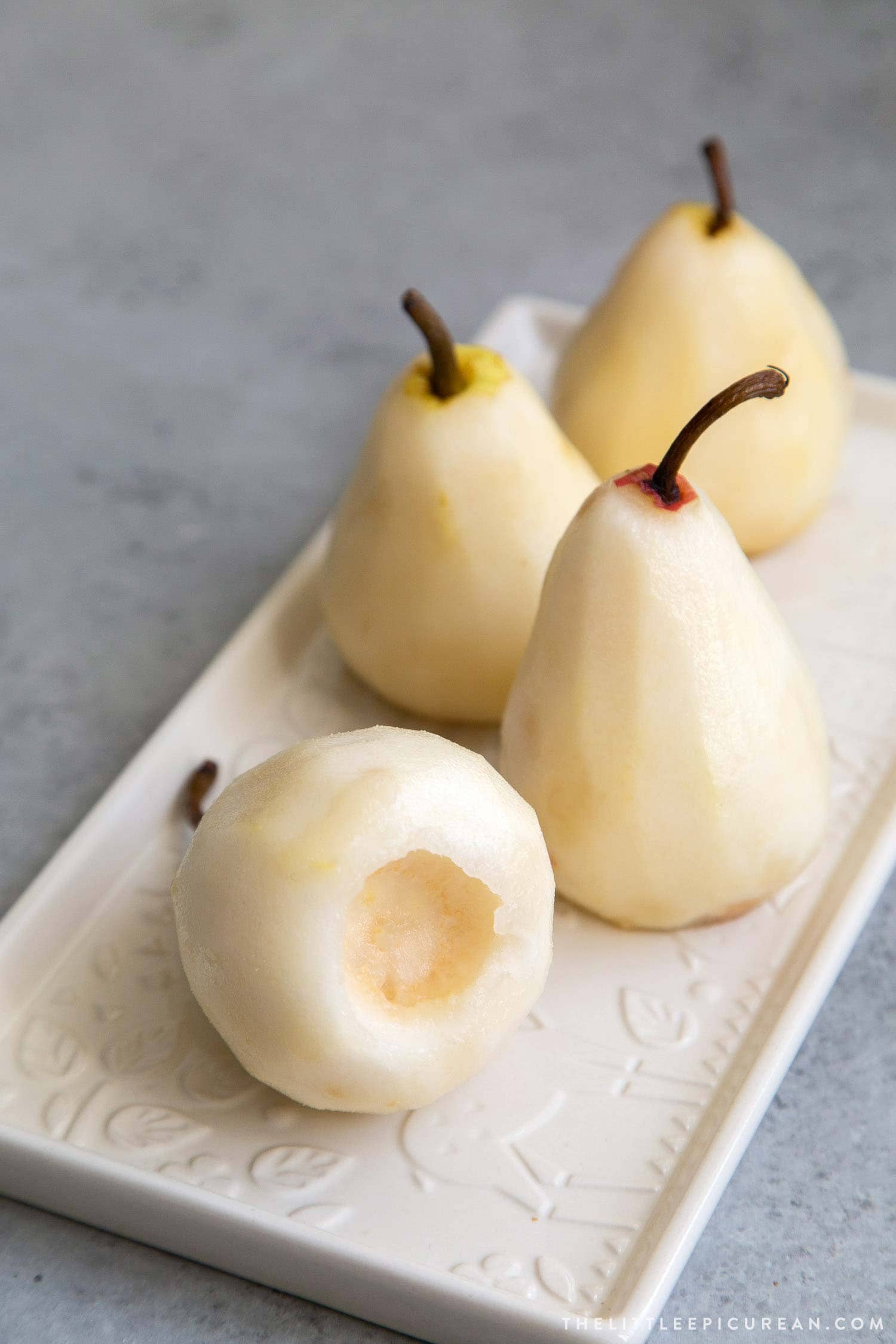 How to Poach Pears: peel pears, slice off 1/4-inch off bottom to flatten. Core out seeds from the bottom of pear. 