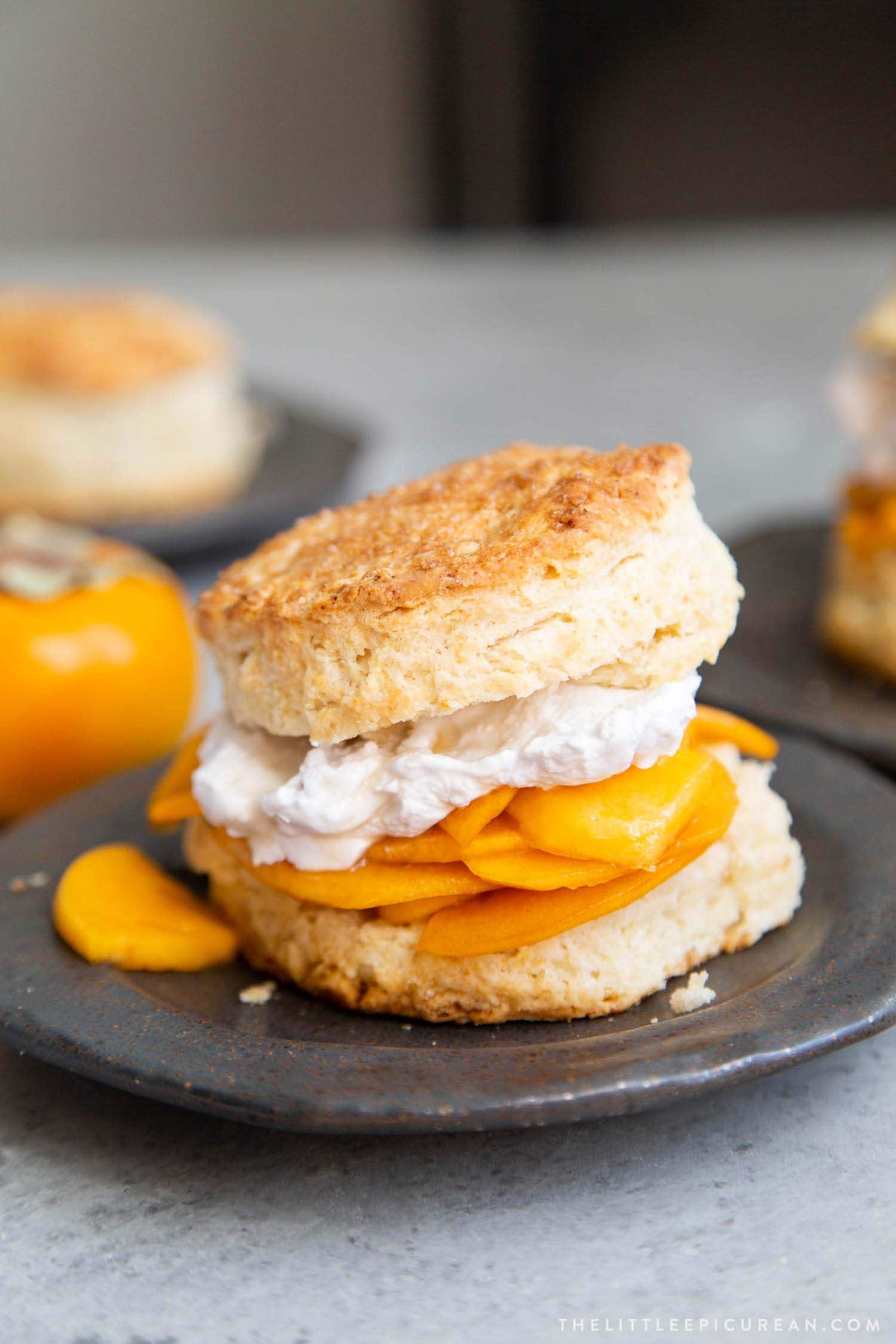 Coconut Persimmon Shortcake. A new spin strawberry shortcake. This dessert features coconut milk shortcake biscuits filled with sliced persimmons and coconut whipped cream. #persimmons #fuyupersimmons #fallbaking #shortcake #biscuits