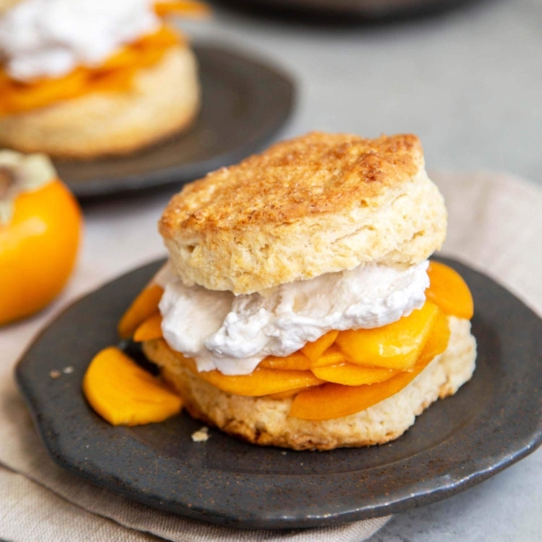 Coconut Persimmon Shortcake. A new spin strawberry shortcake. This dessert features coconut milk shortcake biscuits filled with sliced persimmons and coconut whipped cream. #shortcake #persimmons #fallbaking #falldesserts