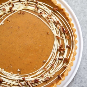 Easy Pumpkin Tart. Tart shell is made with a buttery shortbread crust. The one bowl pumpkin filling is a breeze to a make. It's decorated with melted white chocolate and chopped pecans. #pumpkin #pumpkintart #piesandtarts #dessert #thanksgiving