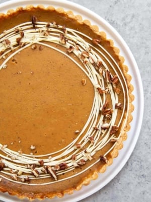 Easy Pumpkin Tart. Tart shell is made with a buttery shortbread crust. The one bowl pumpkin filling is a breeze to a make. It's decorated with melted white chocolate and chopped pecans. #pumpkin #pumpkintart #piesandtarts #dessert #thanksgiving