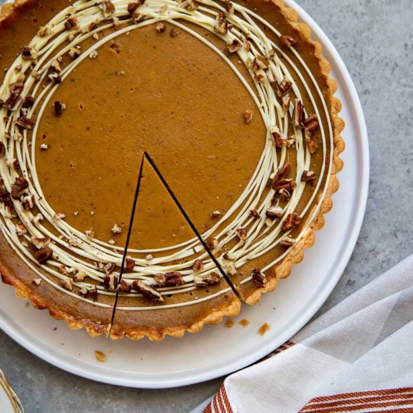 Easy Pumpkin Tart. Tart shell is made with a buttery shortbread crust. The one bowl pumpkin filling is a breeze to a make. It's decorated with melted white chocolate and chopped pecans. #pumpkin #pumpkintart #piesandtarts #dessert #thanksgiving