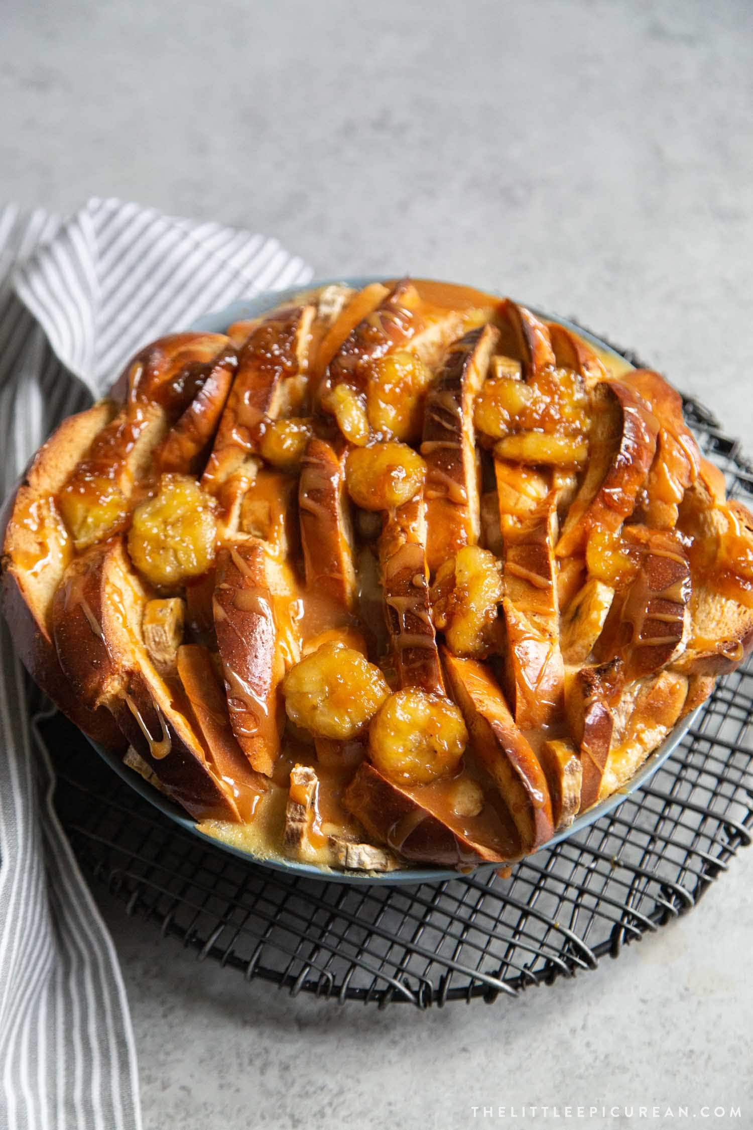 Banana Foster Bread Pudding. Sliced challah bread soaked in spiced custard mixture, baked until golden, and topped with brown sugar cooked bananas and caramel sauce. #breakfast #brunch #breadpudding #dessert #sweet