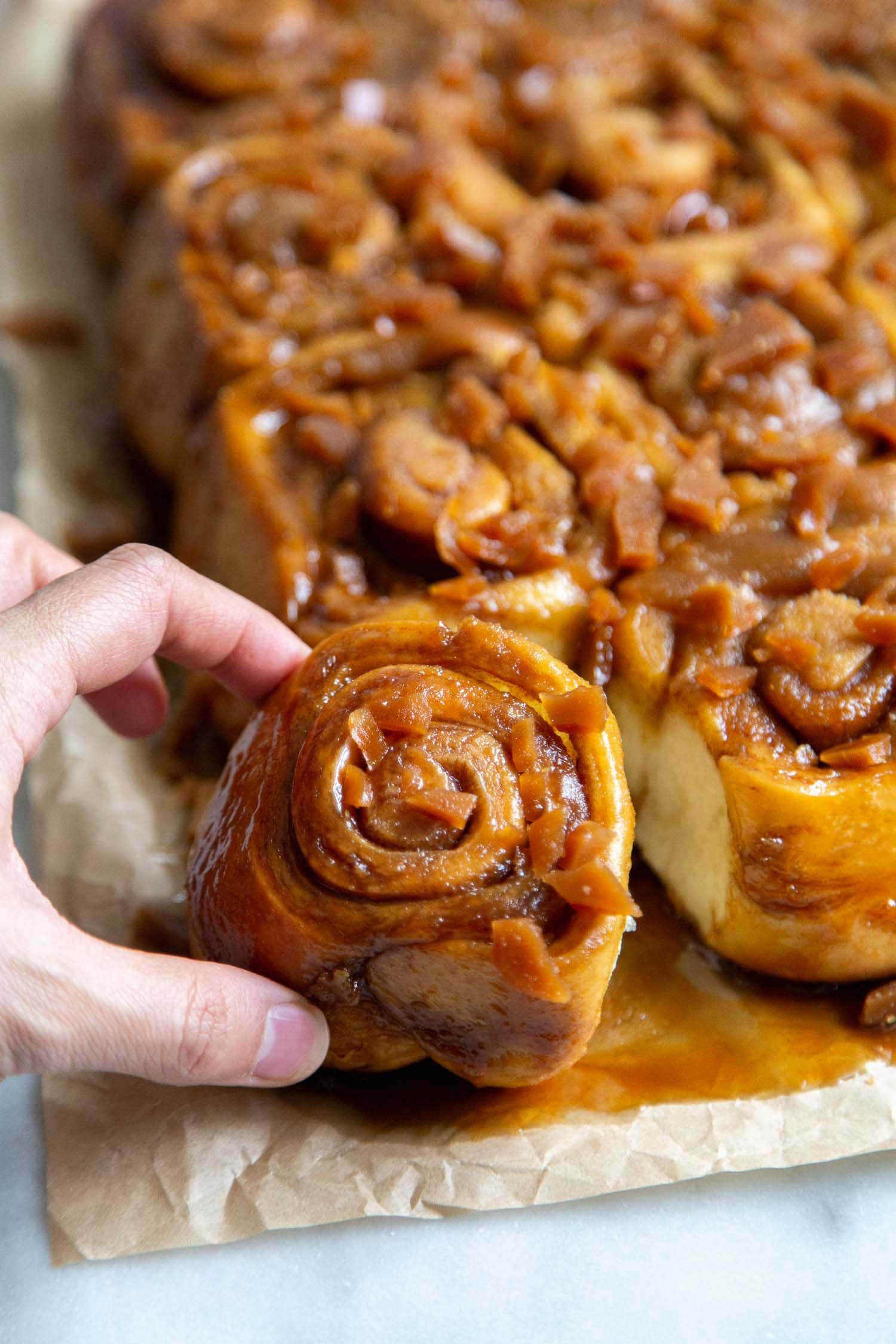 Toffee Sticky Buns. These warm and fluffy buns are filled with cinnamon sugar, coated with a sweet molasses glaze, and topped with chopped toffee bits! #breakfast #brunch #holidays #toffee #stickybuns