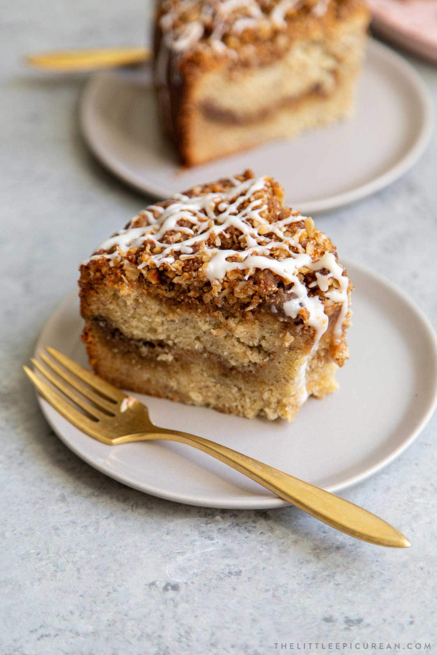 Banana Crumb Cake Slice. Moist banana cake with cinnamon sugar filling topped with walnut oat crumble topping. Finished with maple glaze icing.