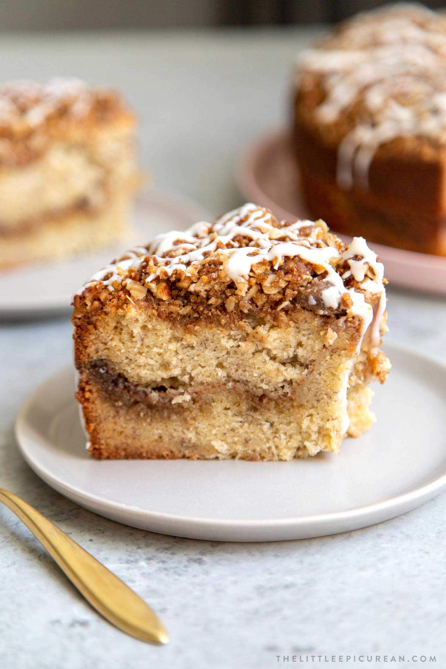 Banana Crumb Cake Slice. Moist banana cake with cinnamon sugar filling topped with walnut oat crumble topping. Finished with maple glaze icing.