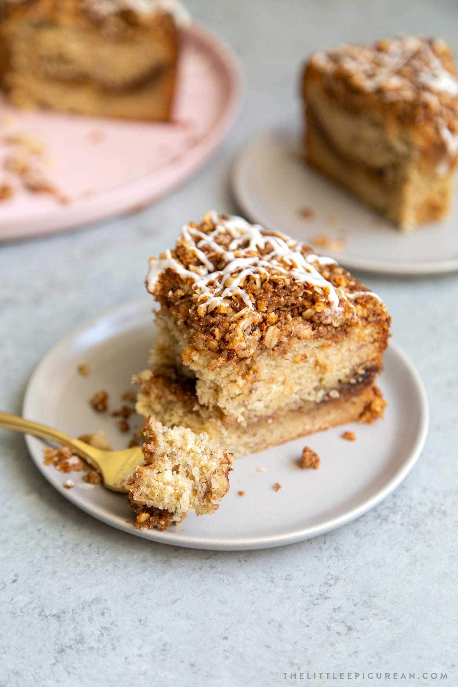 Banana Crumb Cake Slice. Moist banana cake with cinnamon sugar filling topped with walnut oat crumble topping. Finished with maple glaze icing.