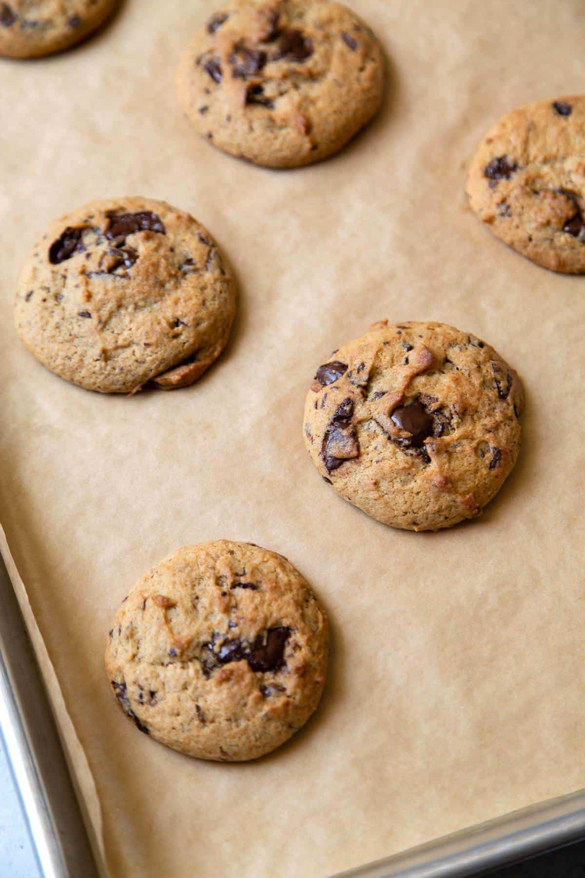 Banana chocolate chip cookies on parchment lined sheet tray.