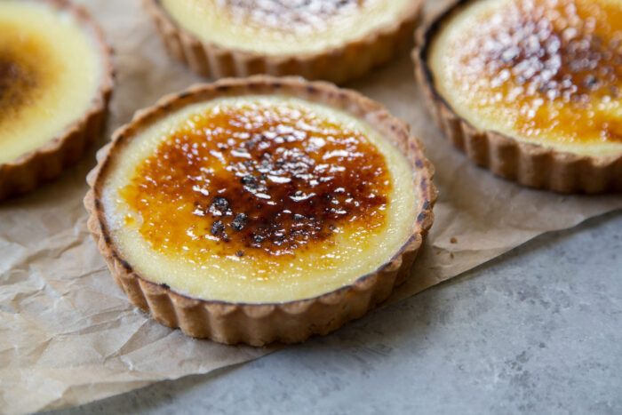 landscape close up of mini creme brulee tart dessert on parchment paper.