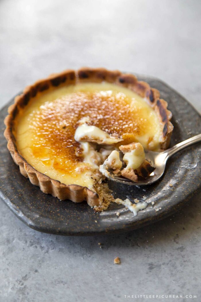 mini creme brulee tart on small plate cut into with fork.