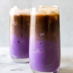 two glasses of iced ube latte. purple milk featured at the bottom with espresso floating on top.