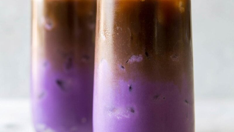 two glasses of iced ube latte. purple milk featured at the bottom with espresso floating on top.