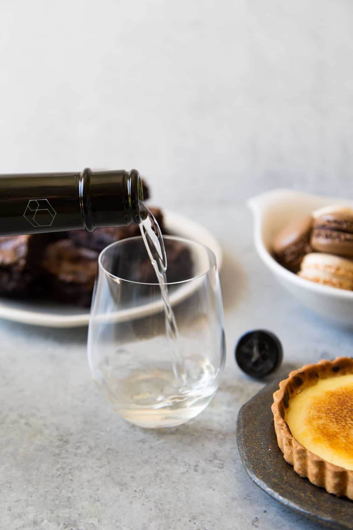 chilled sake being poured into stemless white wine glass.