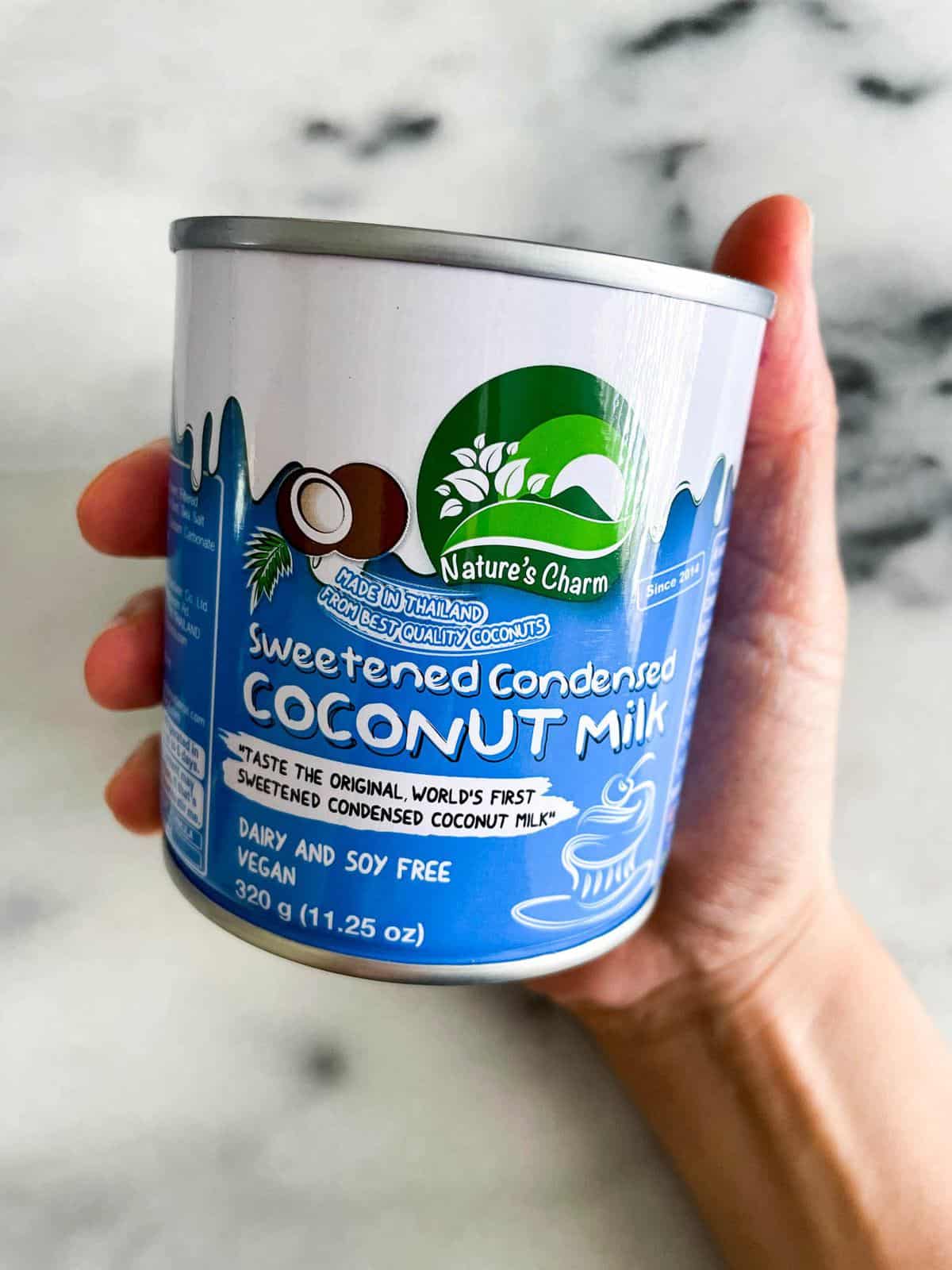 hand holding a can of unopened sweetened condensed coconut milk