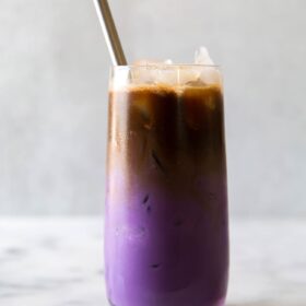 iced ube latte served in a tall glass with a metal straw