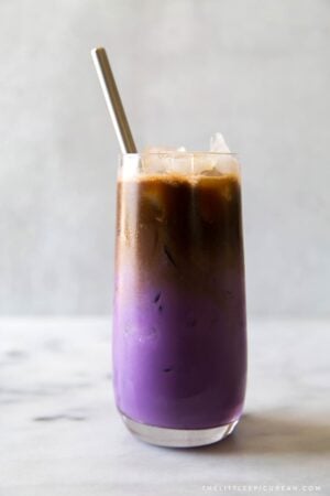 iced ube latte served in a tall glass with a metal straw
