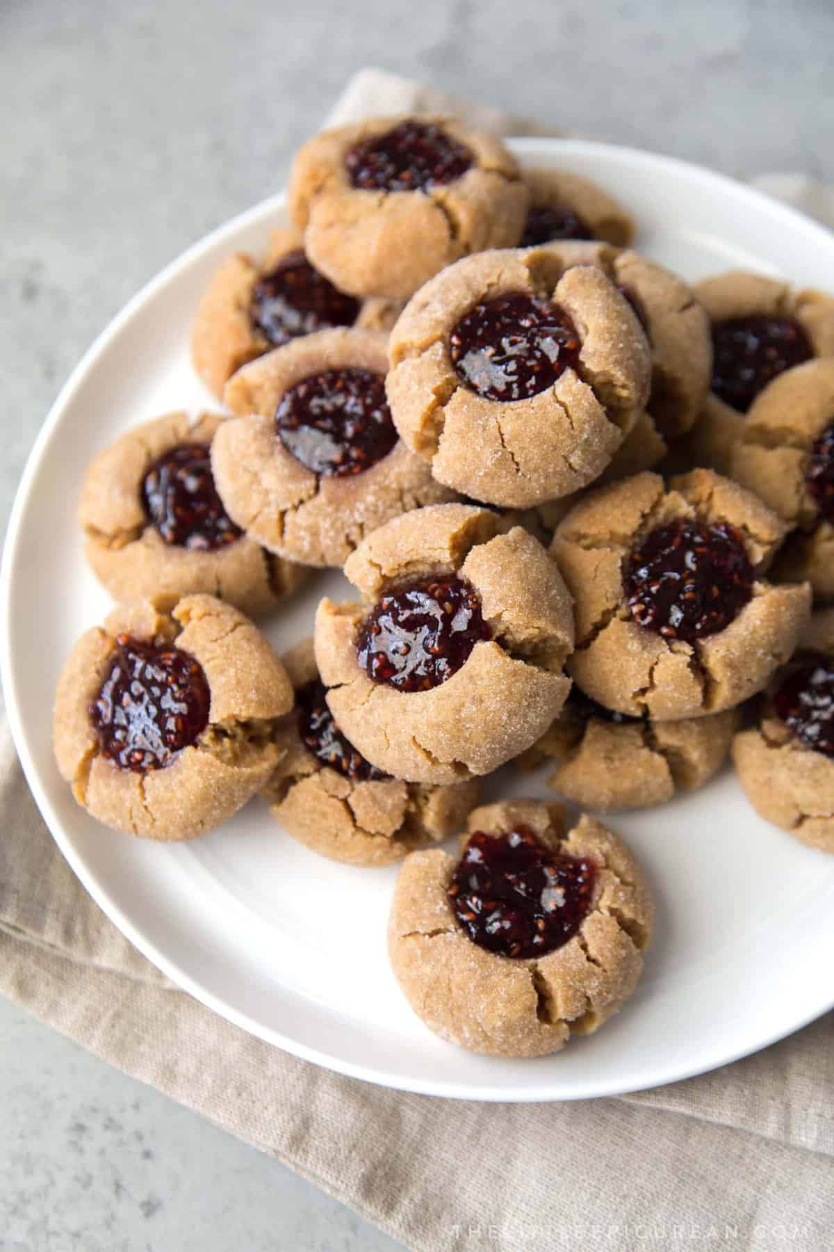 peanut butter thumbprint cookies filled with jelly on white serving plate.