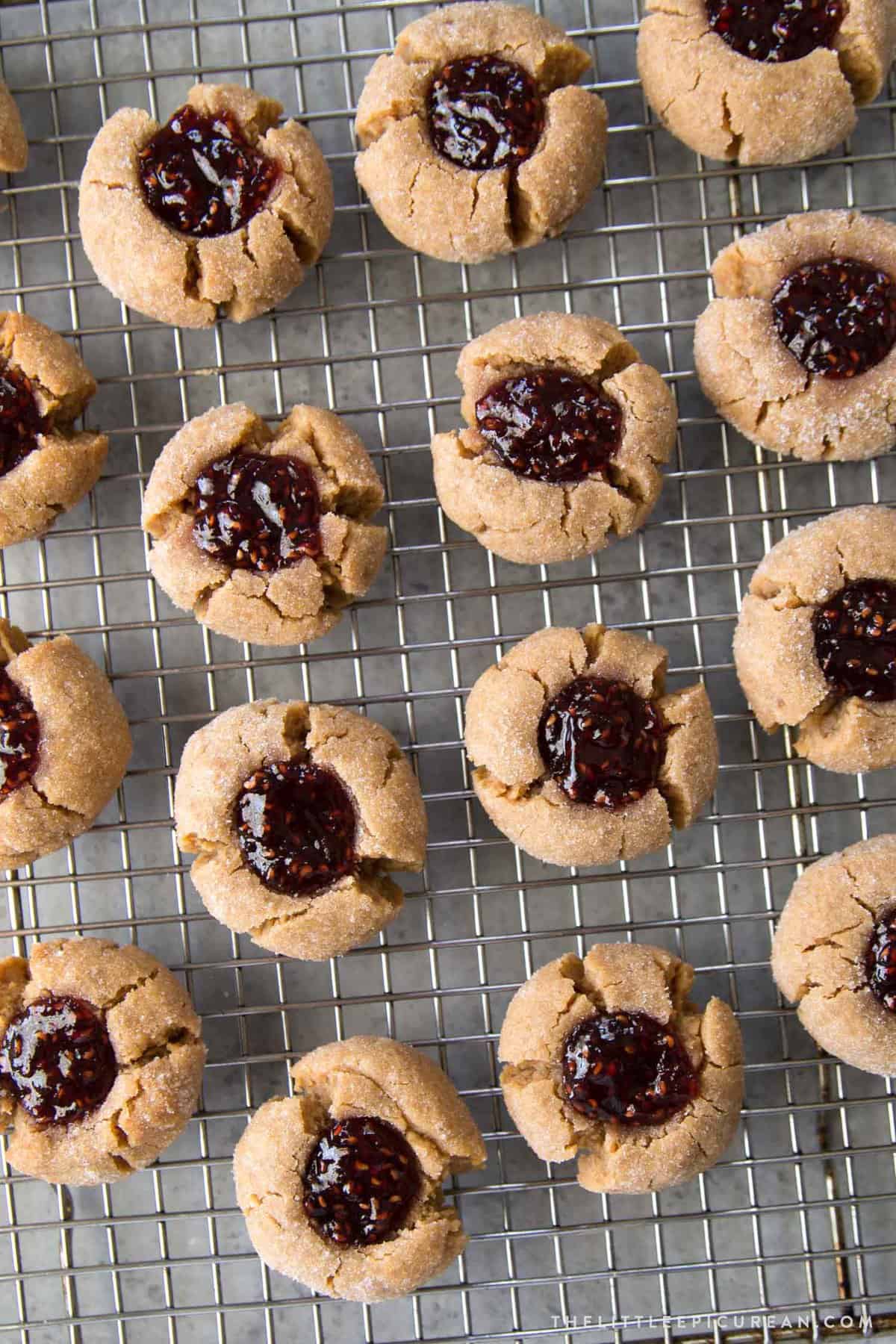 a dozen peanut butter thumbprint cookies on wire rack.