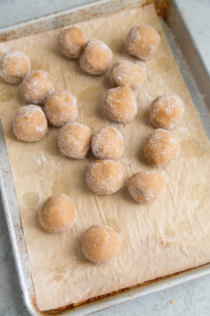 peanut butter cookie balls rolled in sugar on parchment lined baking sheet.