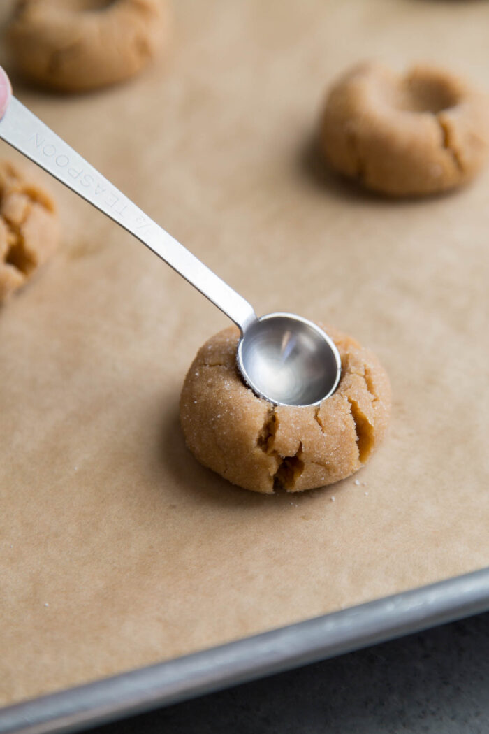 peanut butter cookie dough pressed with teaspoon on baking sheet.