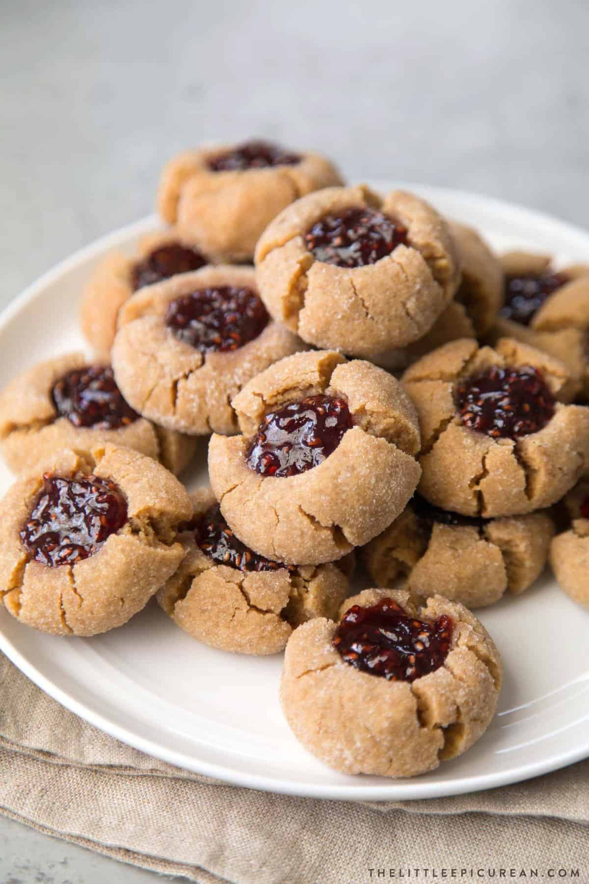 a dozen peanut butter thumbprints on a white plate.