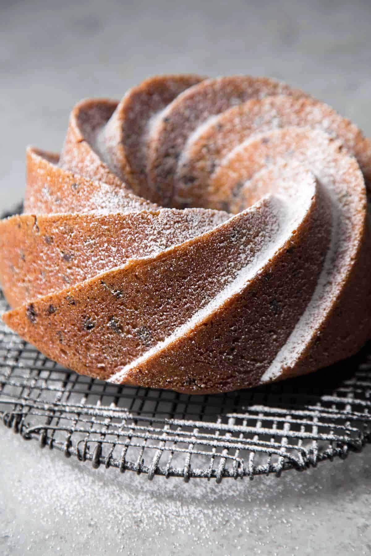 powder sugar dusted chocolate chip bundt cake on black wire rack. 