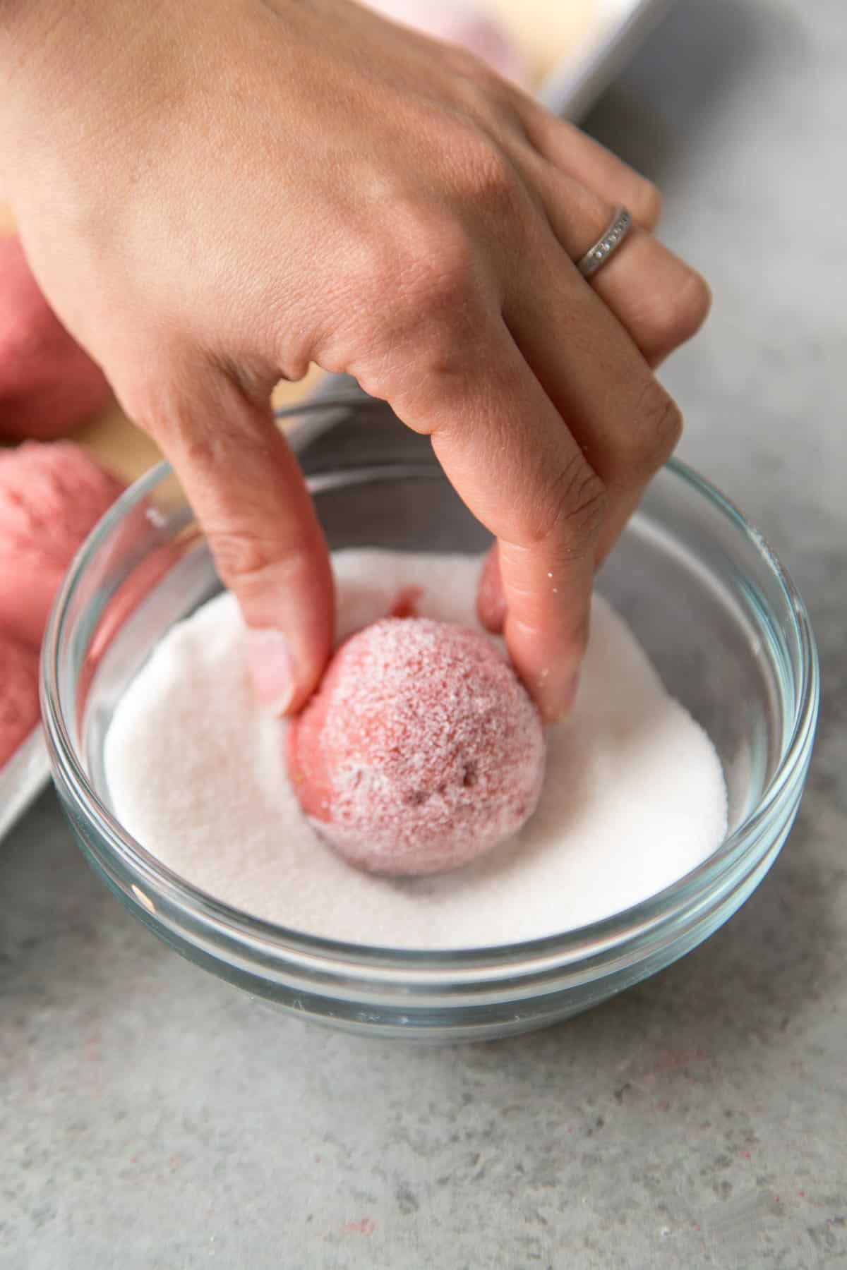 rolled portioned strawberry cookie dough in granulated sugar.