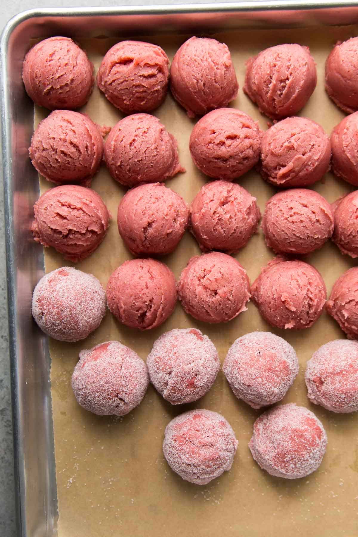 strawberry sugar cookie dough balls on parchment lined baking sheet.