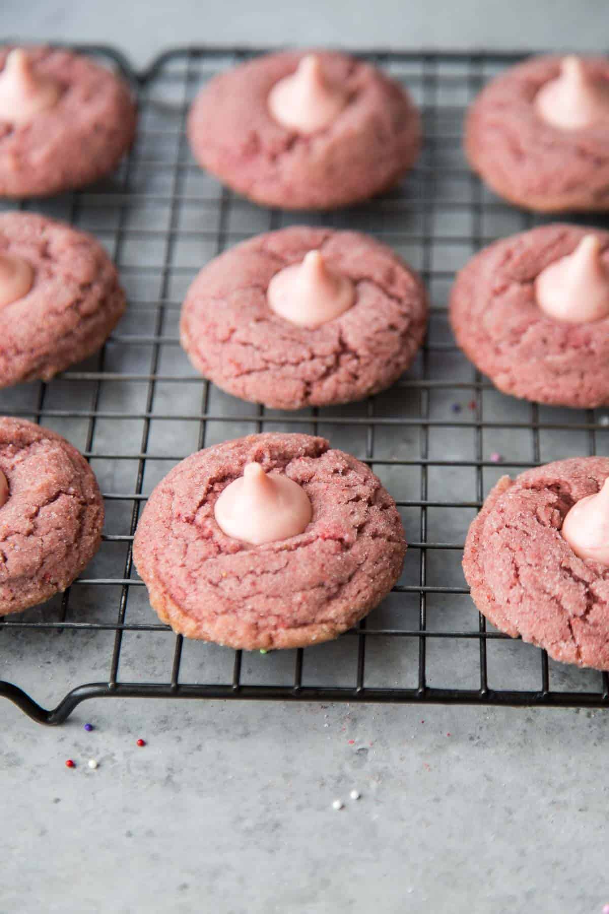 strawberry kiss cookies on black wire rack cooling.