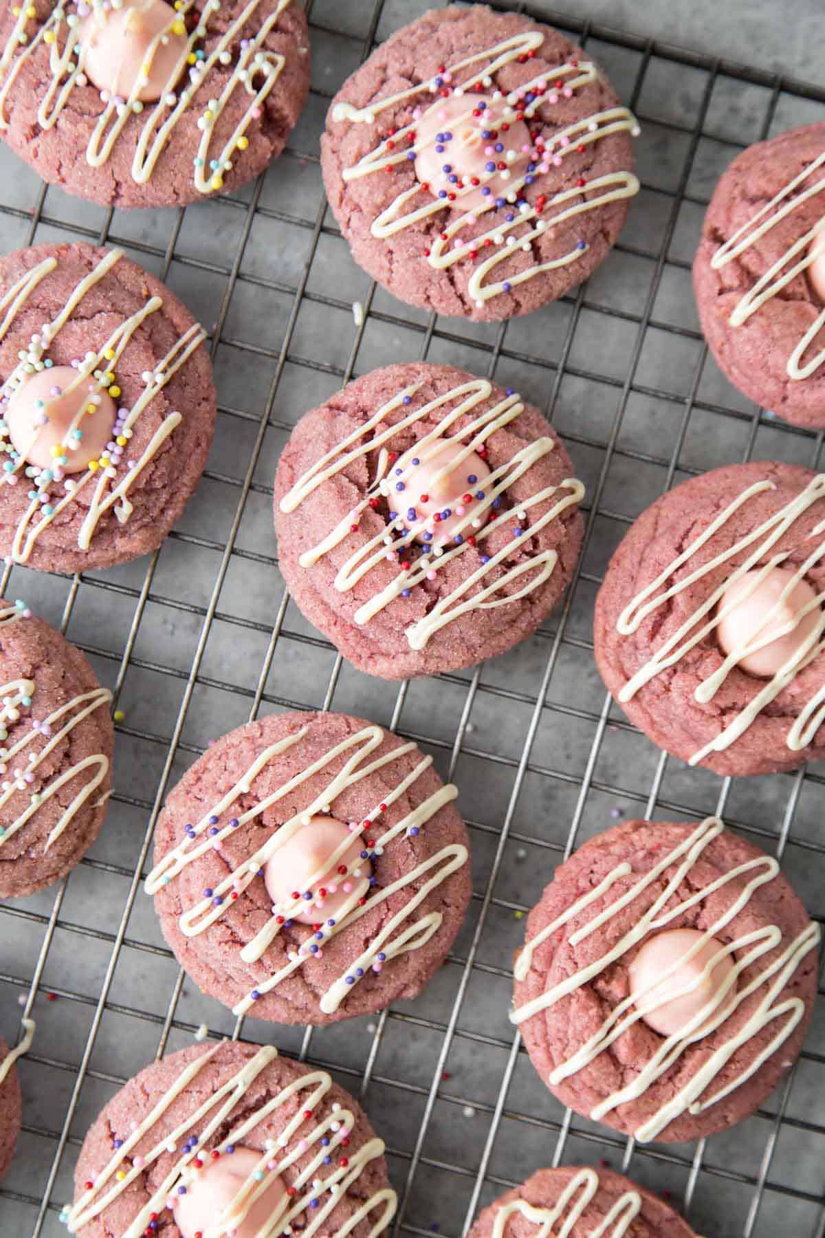 strawberry kiss cookies with white chocolate drizzle and assorted colorful sprinkles.