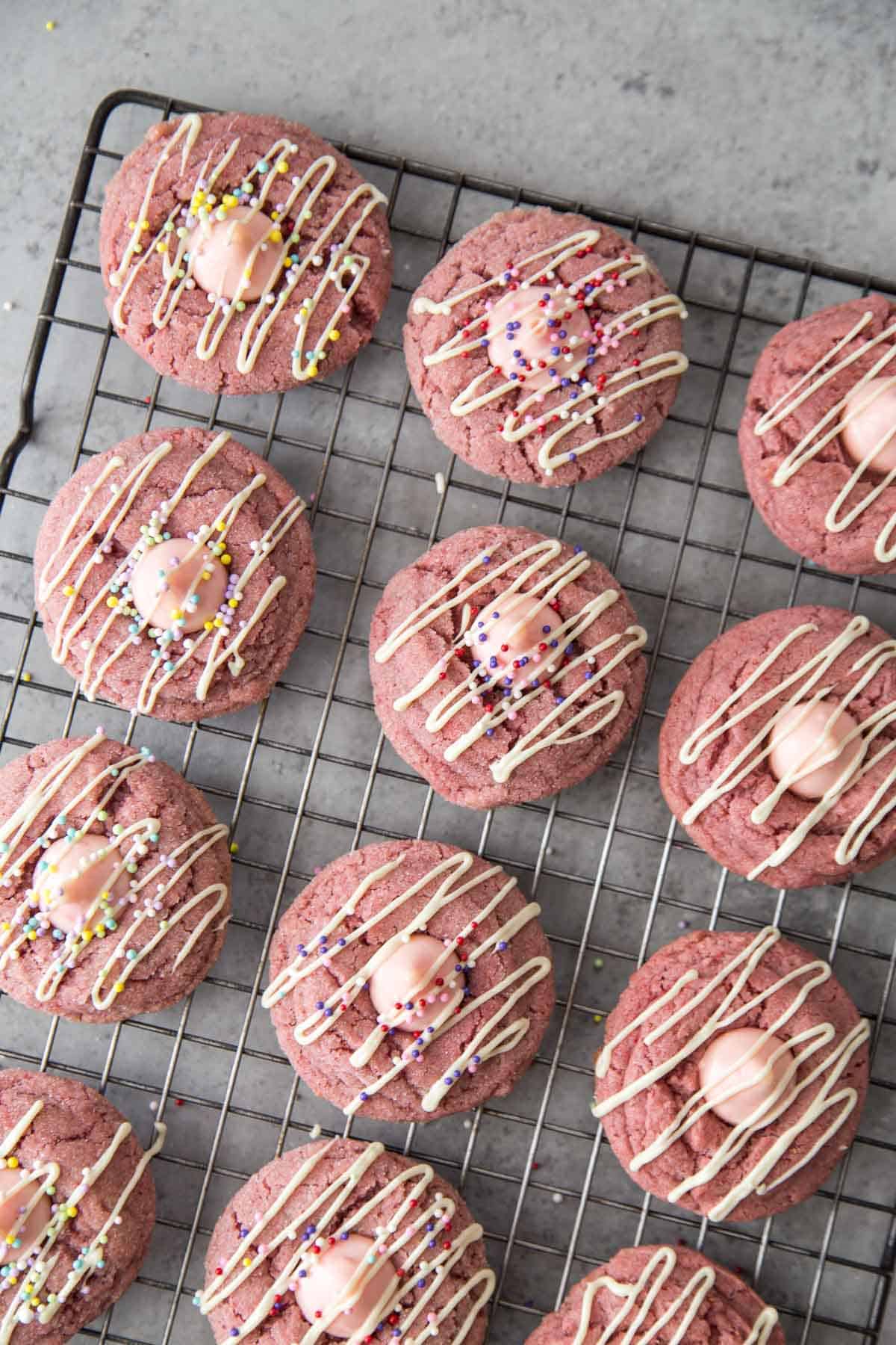 strawberry kiss cookies with white chocolate drizzle and assorted colorful sprinkles.