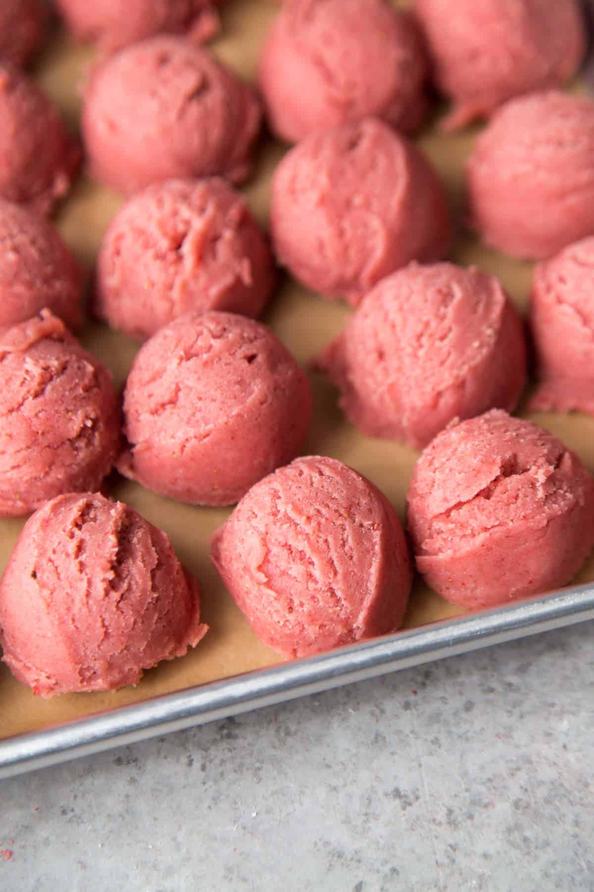 scooped strawberry sugar cookie dough on parchment lined baking sheet.