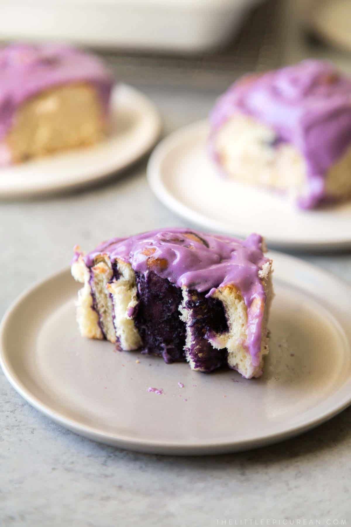 ube bread rolls filled with ube halaya and topped with ube cream cheese frosting.