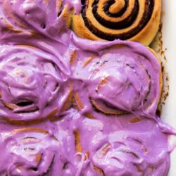 ube bread rolls topped with ube cream cheese frosting.