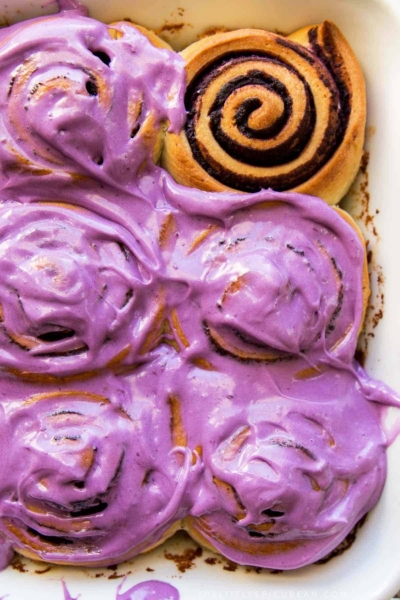 ube bread rolls topped with ube cream cheese frosting.
