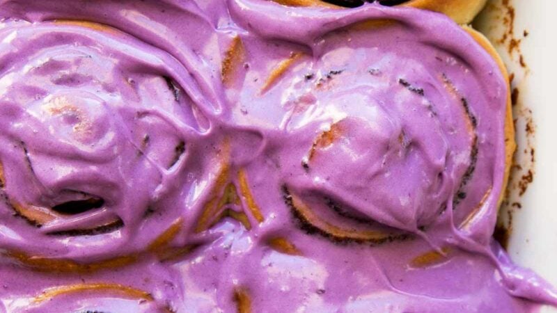 ube bread rolls topped with ube cream cheese frosting.