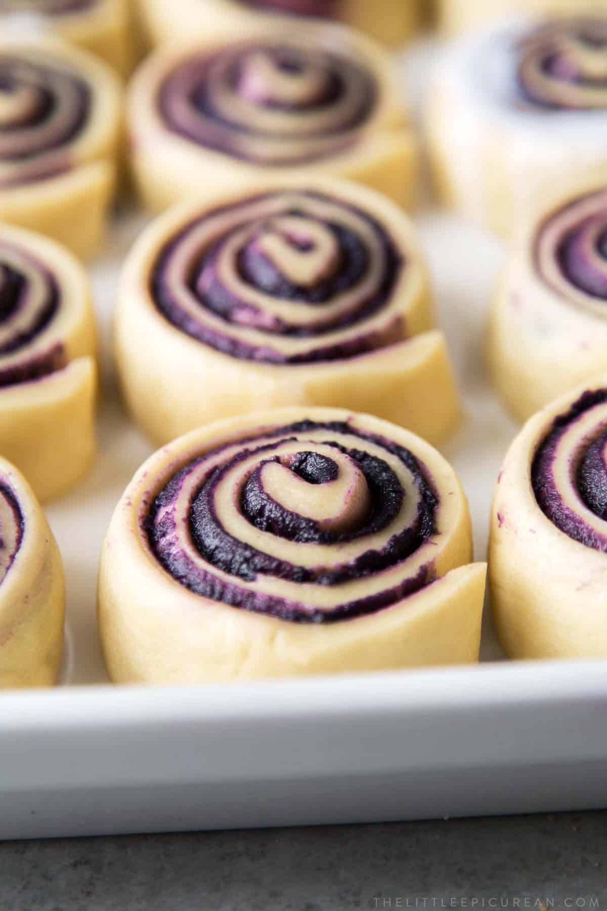 pour coconut milk over proofed ube bread rolls before baking.