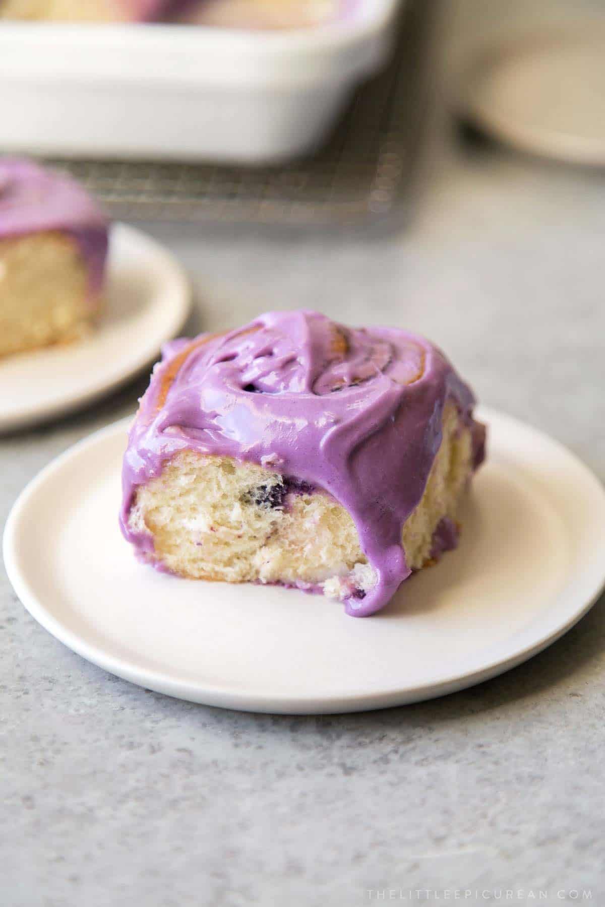 ube bread rolls topped with ube cream cheese frosting.