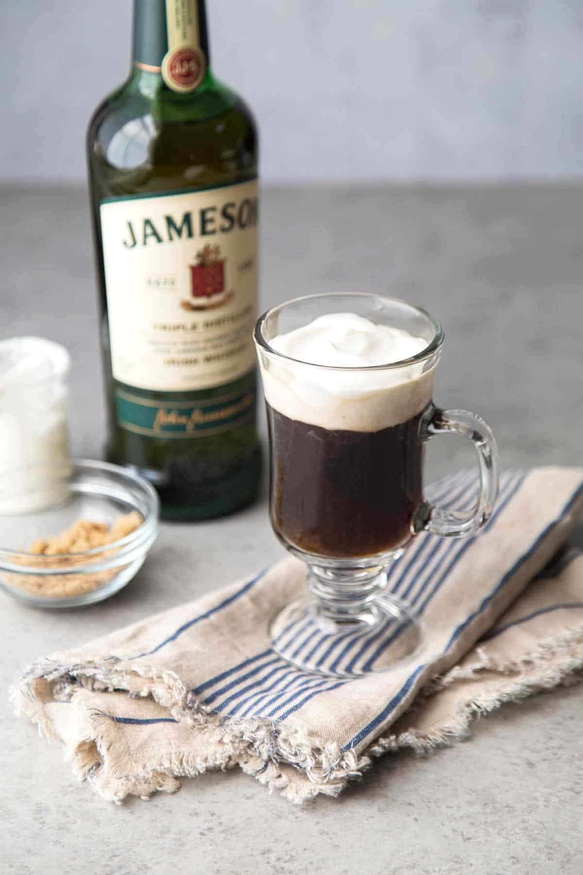 Irish coffee topped with light whipped cream in a clear mug.