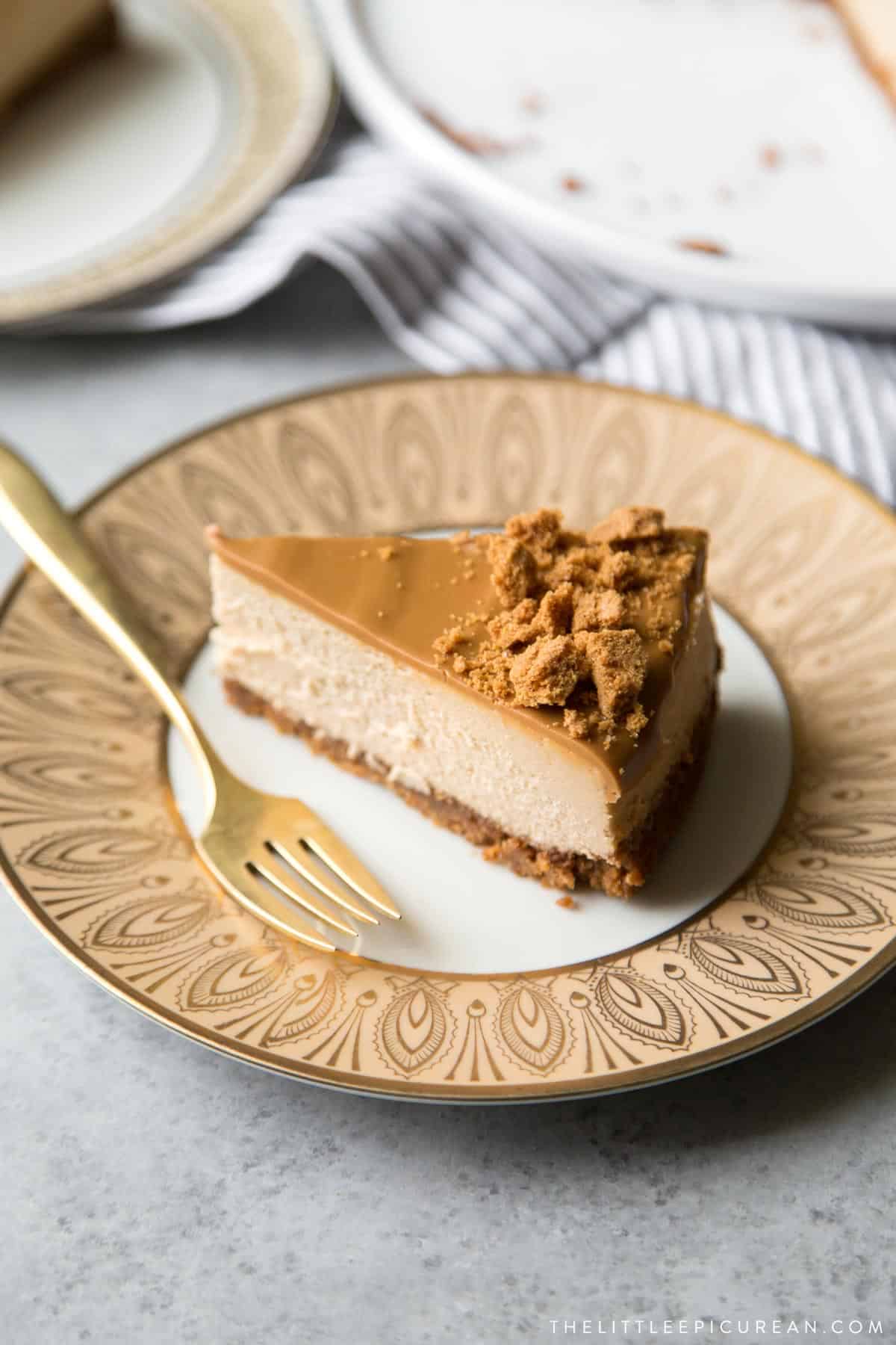 slice of biscoff cheesecake on decorative gold dessert plate.