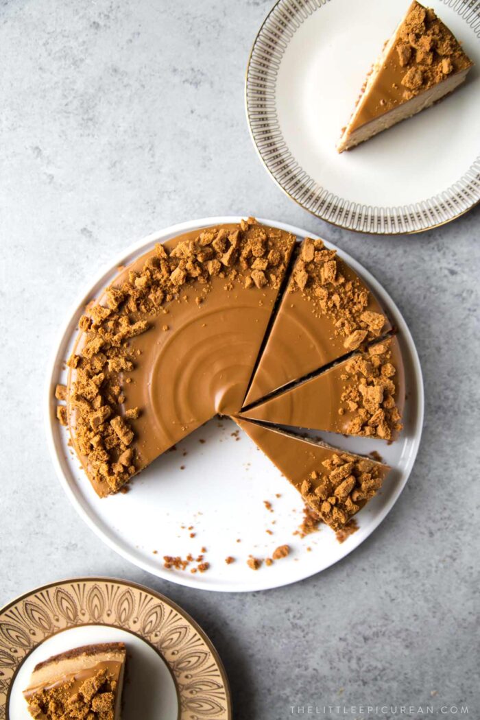 overhead of sliced cookie butter biscoff cheesecake on white serving plate.